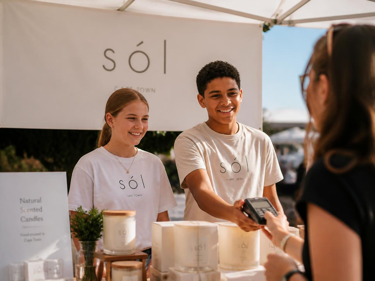 A teenager making a sale to a customer at a market stall